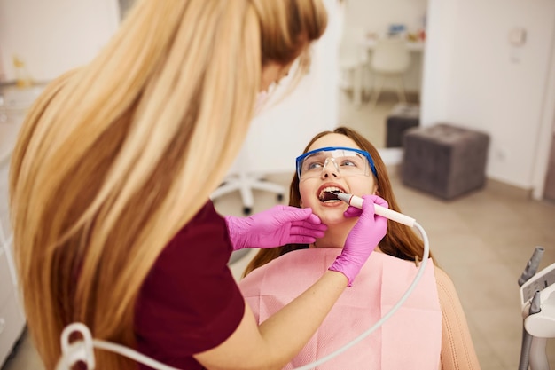 Niña con gafas protectoras visitando al dentista en la clínica Concepción de estomatología