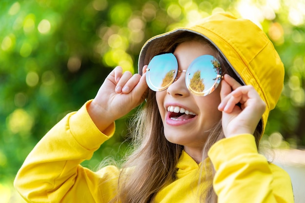 Una niña con gafas de sol mira a lo lejos y sonríe Un hermoso niño disfruta de la naturaleza que lo rodea
