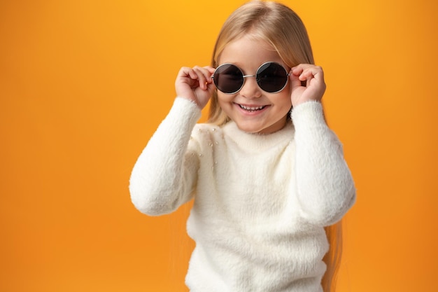 Niña con gafas de sol sobre un fondo amarillo