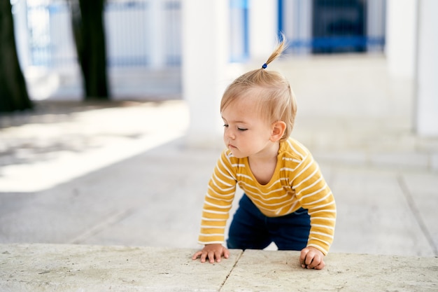 Niña gatea sobre baldosas en el patio de la casa