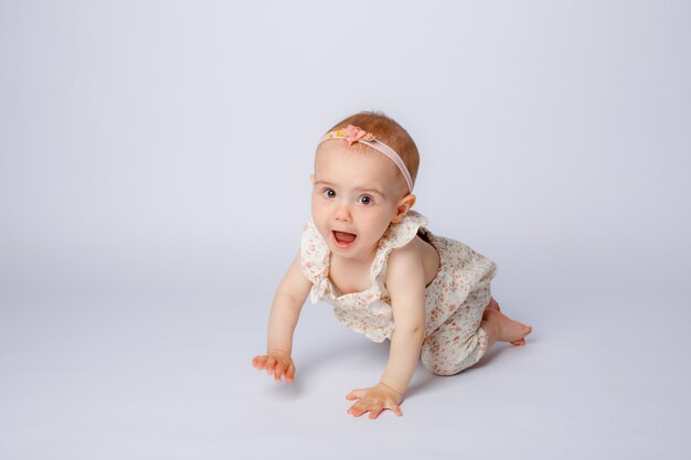 Niña gateando sobre un fondo blanco en el estudio