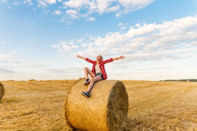 Niña en gavillas de paja en un campo