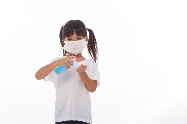 Niña con gel de alcohol para limpiar las manos en blanco.