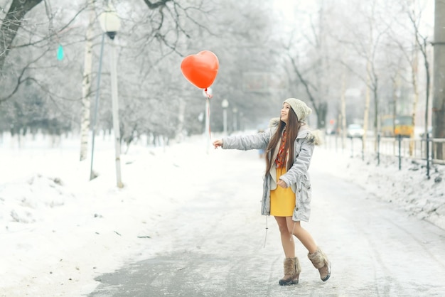 niña con globo de corazón fuera de invierno