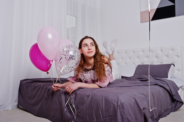 Niña con globos en la cama posó