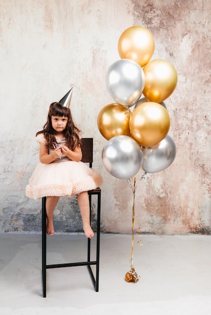 Una niña con globos el niño celebra su cumpleaños el bebé está sentado en una silla junto a los globos