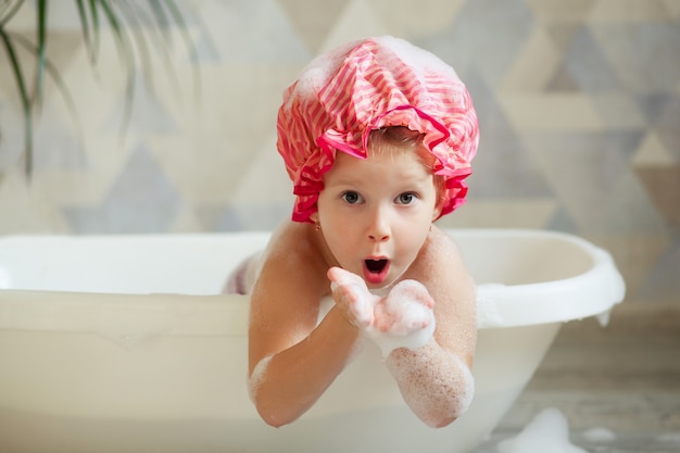 Niña con gorra rosa, tomando un baño de burbujas