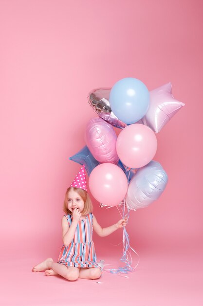 Niña con una gorra se sienta con un montón de globos