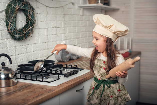 Niña con gorro de cocinero ayuda en la cocina a cocinar