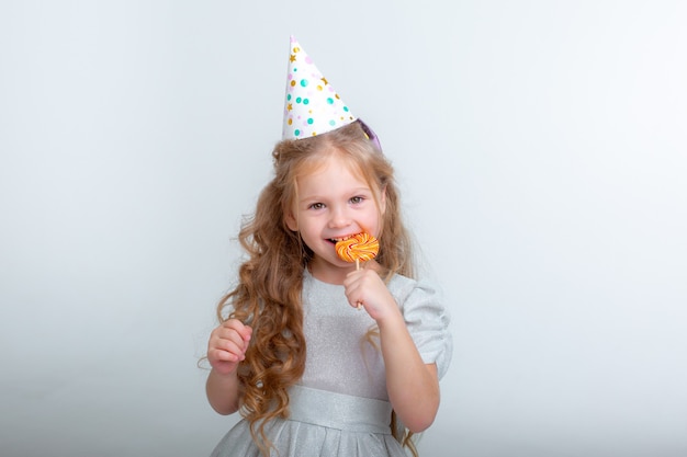 Niña con un gorro de cumpleaños con una piruleta