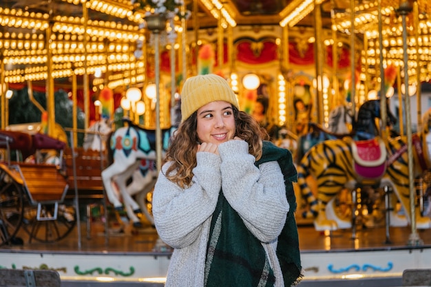 Niña con gorro de lana amarillo y bufanda en una feria de Navidad