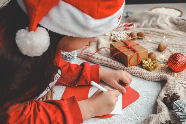 Niña con gorro de Papá Noel escribe carta a Papá Noel