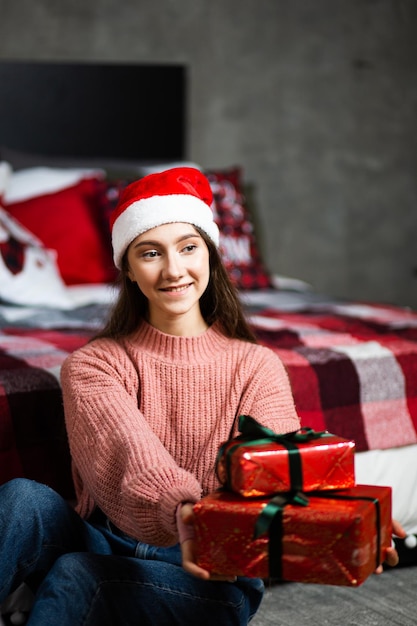 Una niña con un gorro de Papá Noel con regalos en el fondo del interior de Año Nuevo.