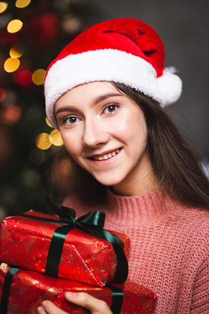 Una niña con un gorro de Papá Noel con regalos en el fondo del interior de Año Nuevo.