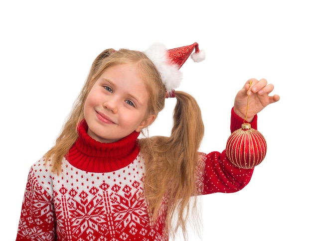Niña con gorro de Papá Noel y suéter navideño con bola de decoración navideña