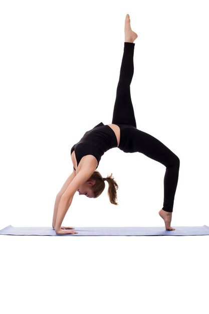 Niña graciosa haciendo puente de gimnasia en la alfombra