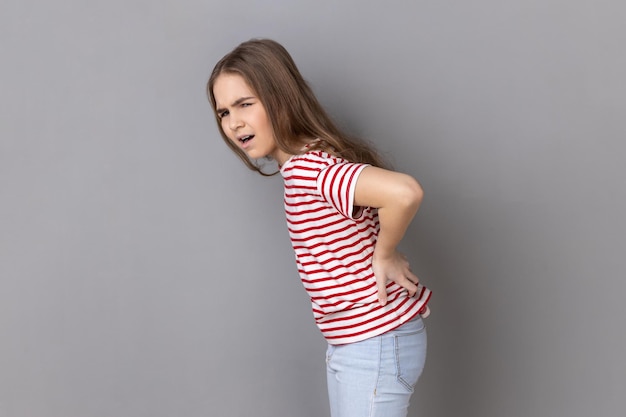 Niña gritando de dolor agudo y reteniendo el dolor de espalda riesgo de enfermedad de cálculos renales