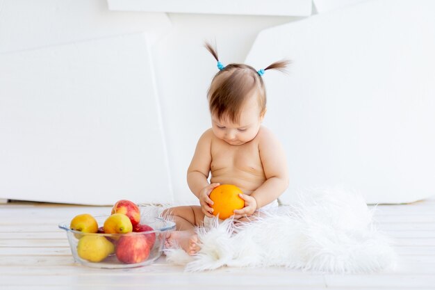 Una niña en una habitación luminosa sentada con un plato de fruta.