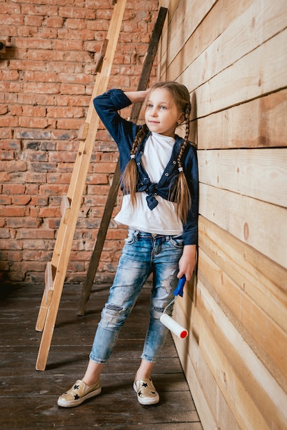 Niña en una habitación con una pared de madera. Construcción