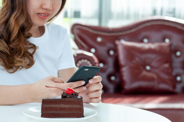 Una niña hablando en línea a través de un video de teléfono móvil sentado en una cafetería. El concepto de conexión inalámbrica a redes y tecnología moderna.