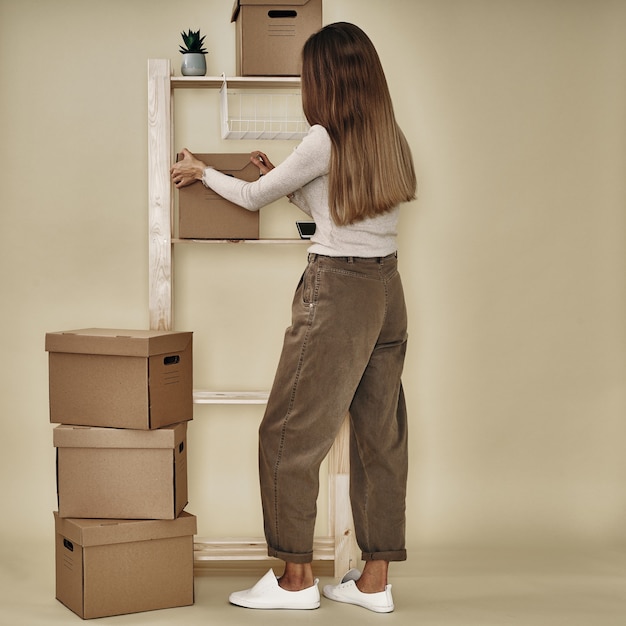La niña hace cajas de papel en un estante de madera. Almacenamiento y embalaje ecológicos.