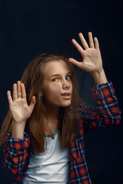 Niña hace cara apoyada contra el cristal