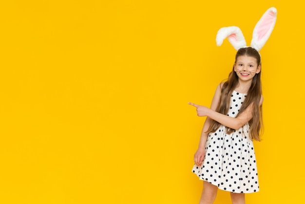 Una niña hace caras de conejo disfrazadas de orejas rosadas de un conejito de Pascua en un niño al comienzo de las vacaciones de Pascua el niño está feliz por las vacaciones de Pascua que han llegado