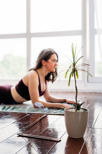 La niña hace ejercicios, estiramientos, yoga, o cerca de la ventana, traje de yoga, cuerpo, delgadez y salud, incienso, plantas, olor