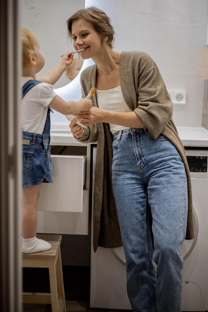 Niña hace a su madre maquillaje con una brocha para polvos en el baño