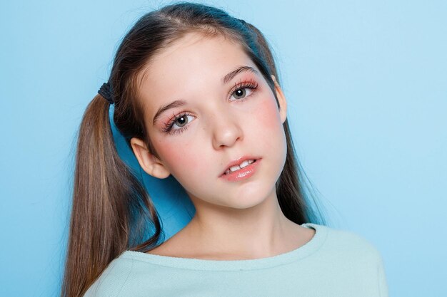 Foto niña haciendo caras y divirtiéndose en la cámara aislada sobre fondo azul