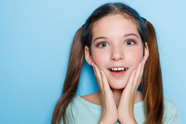 niña haciendo caras y divirtiéndose en la cámara aislada sobre fondo azul