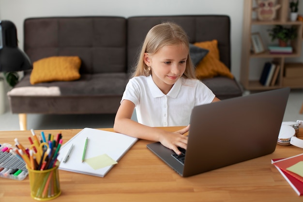 Foto niña haciendo clases online desde casa