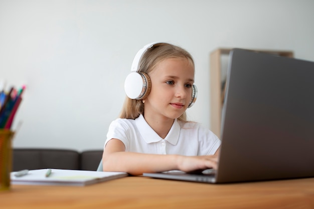 Foto niña haciendo clases online desde casa