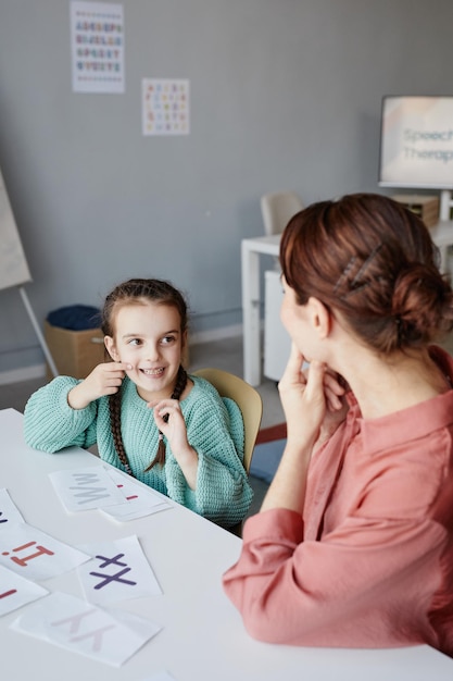 Niña haciendo ejercicios articulados junto con su maestra en la mesa del aula