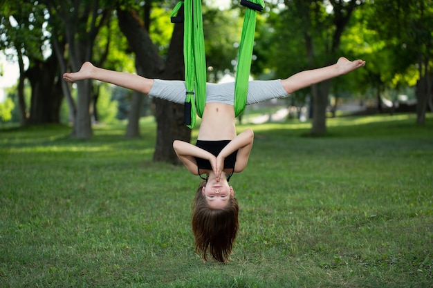 Niña haciendo ejercicios de yoga con una hamaca en el parque