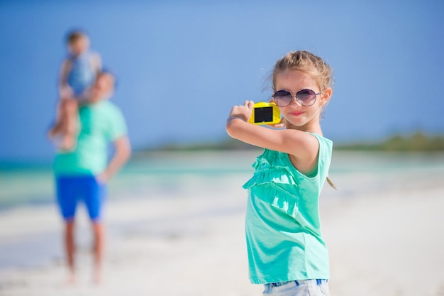 Niña haciendo fotos en el teléfono de la familia en la playa