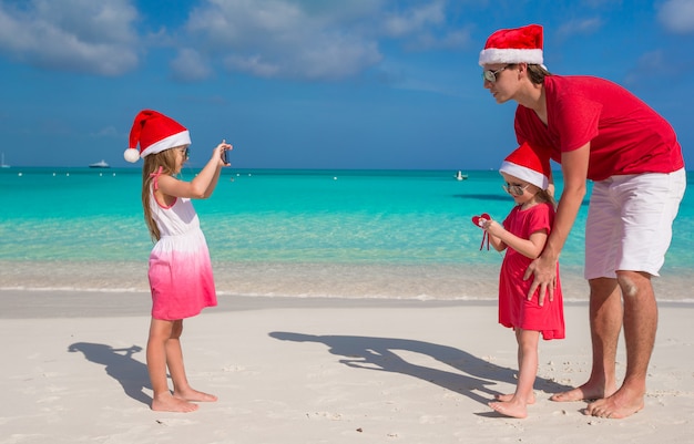 Niña haciendo fotos en el teléfono de su familia en la playa