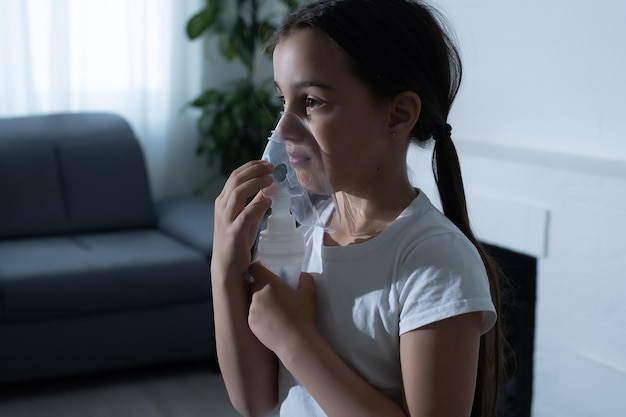 Niña haciendo inhalación con nebulizador en casa. niño asma inhalador inhalación nebulizador vapor enfermo tos concepto.