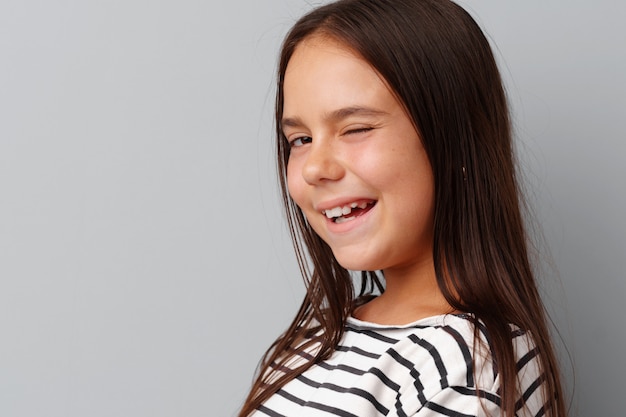 Niña haciendo una mueca sobre un fondo gris