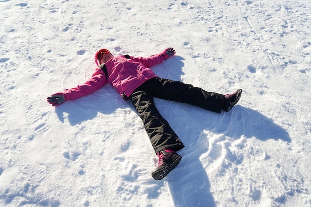 Niña haciendo un muñeco de nieve con ropa de nieve