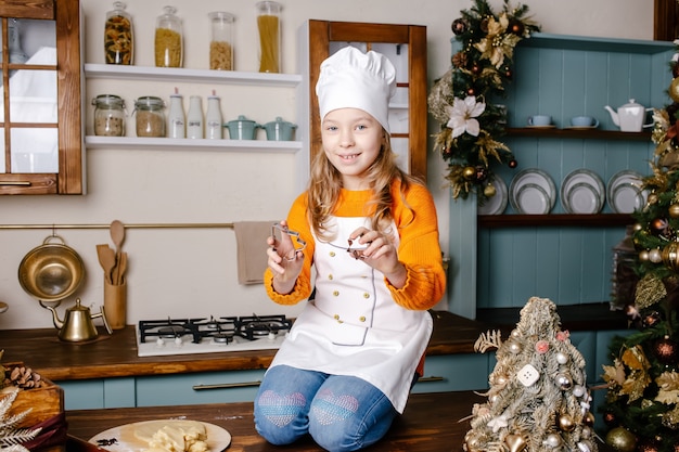 Niña haciendo pan de jengibre de Navidad en la cocina en el salón decorado Hornear y cocinar con niños para Navidad en casa