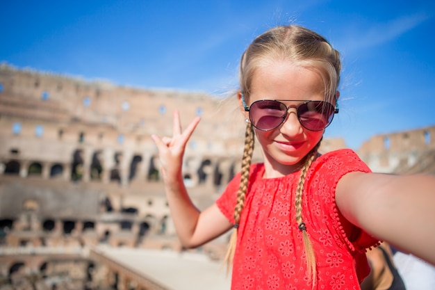 Niña haciendo selfie en Coliseo, Roma, Italia. Retrato de niño en lugares famosos de Europa