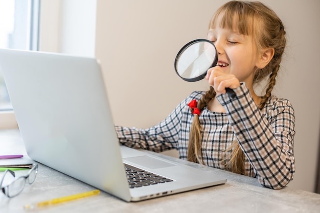 Niña haciendo su tarea en casa y usando una computadora portátil