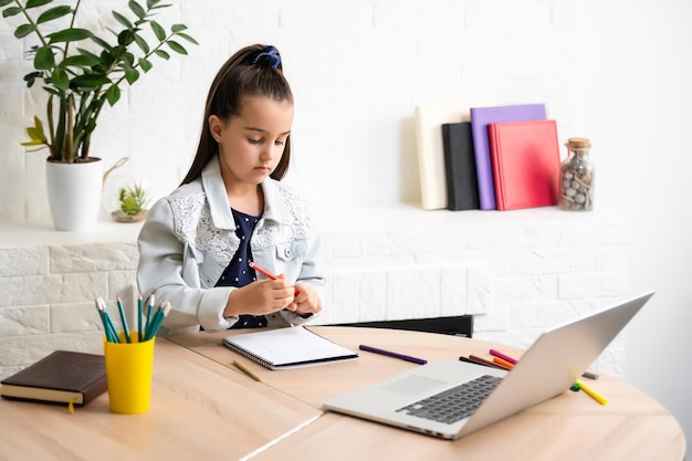 Niña haciendo su tarea en casa y usando una computadora portátil