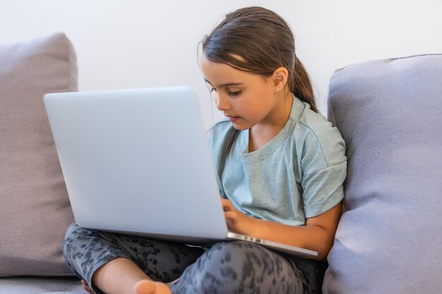 Niña haciendo su tarea en casa y usando una computadora portátil