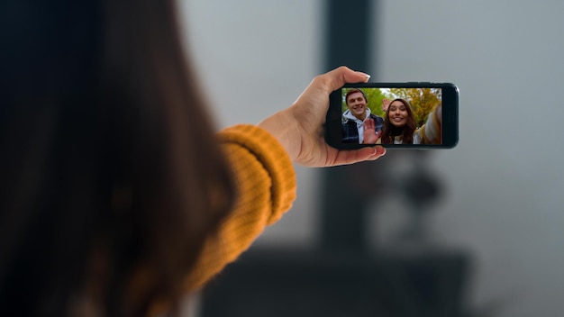 Niña haciendo una videoconferencia con amigos de cerca con las manos agitadas sosteniendo un móvil