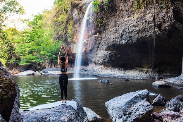 Niña haciendo yoga cerca de una cascada