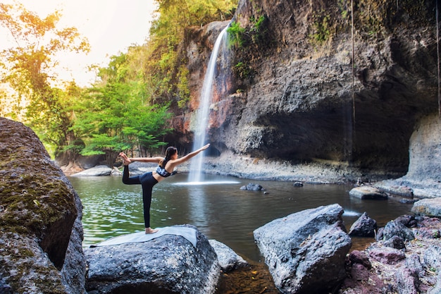 Foto niña haciendo yoga cerca de una cascada