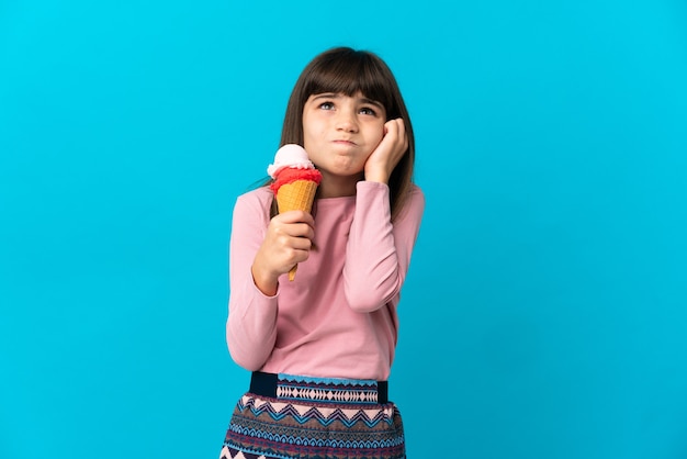 Niña con un helado de cucurucho aislado sobre fondo azul frustrado y cubriendo las orejas