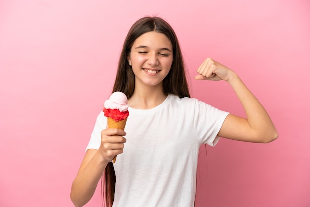 Niña con un helado de cucurucho sobre fondo rosa aislado haciendo gesto fuerte